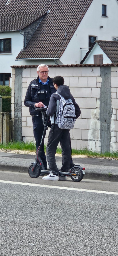 Polizist spricht mit einem E-Scooter Fahrer