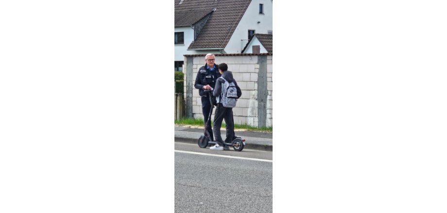 Polizist spricht mit einem E-Scooter Fahrer