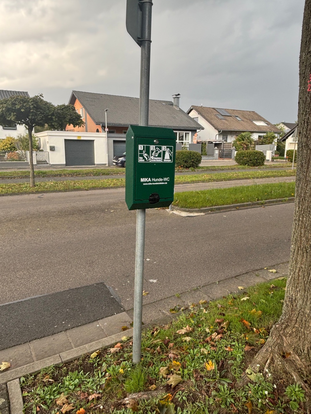 Hundetoilette mit Beutelspender an einem Pfosten am Straßenrand