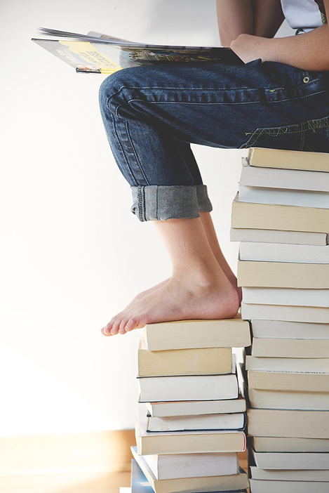 Kind sitzend auf Bücherstapel