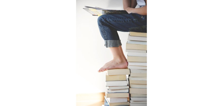 Kind sitzend auf Bücherstapel