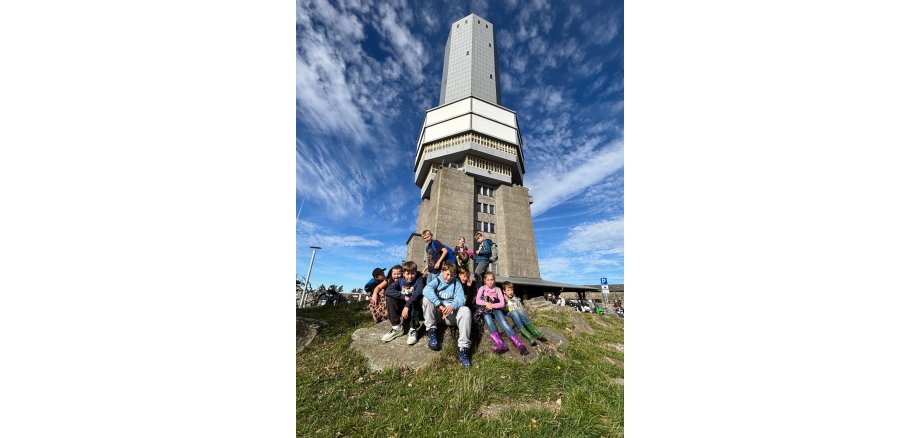 Gruppe sitzt vor Turm auf dem Feldberg