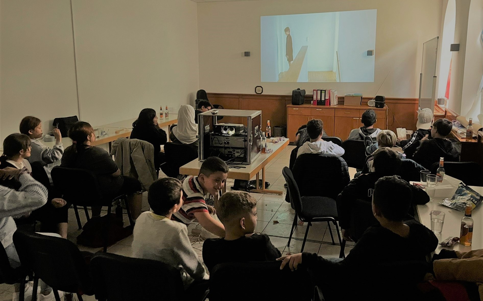 Mehrere Personen sitzen vor einer Leinwand und schauen einen Film