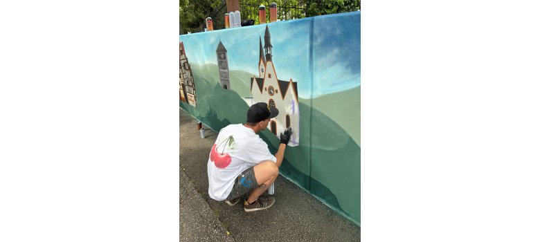 Person malt Graffiti an eine Wand in Bouxwiller