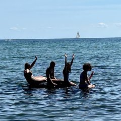 Jugendliche sitzend auf Surfbrett im Wasser