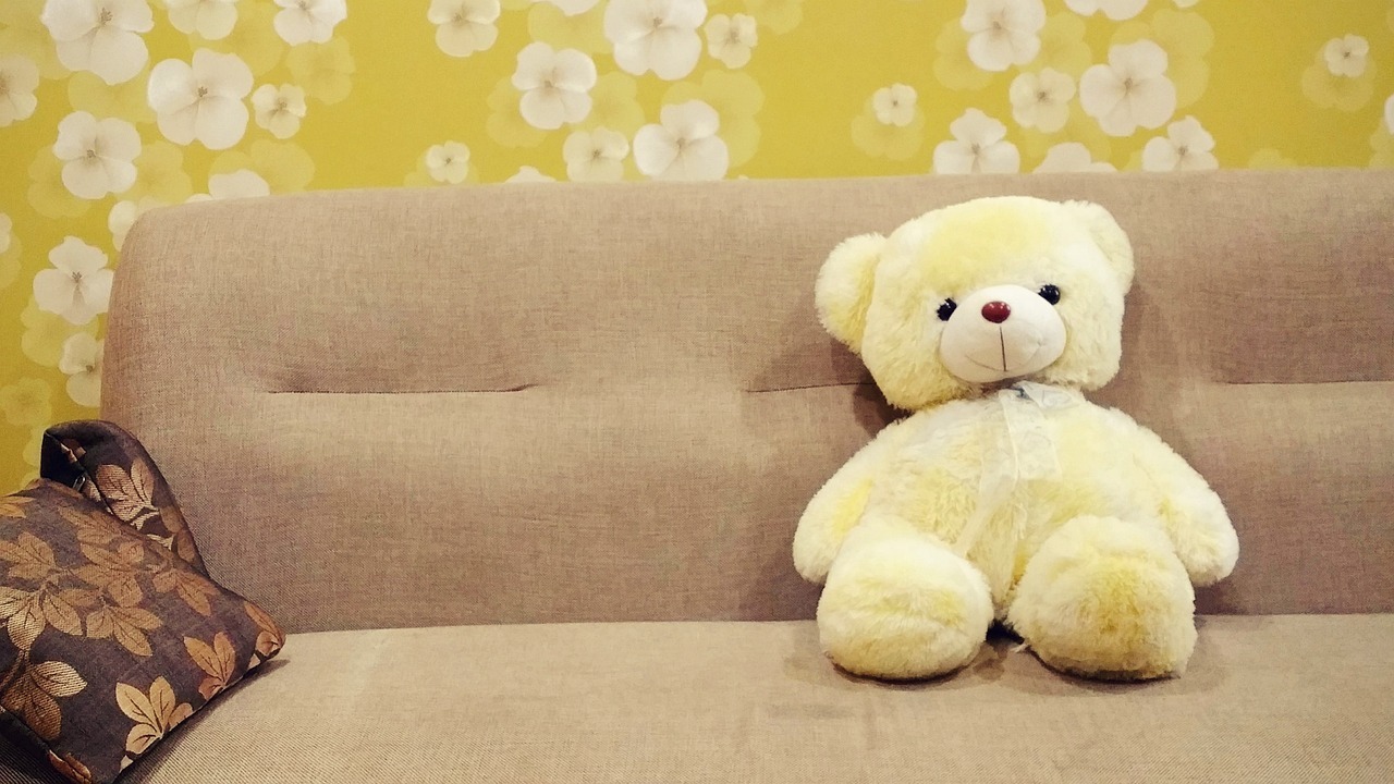 Auf dem Bild sieht man eine Couch mit einem Plüschteddybären