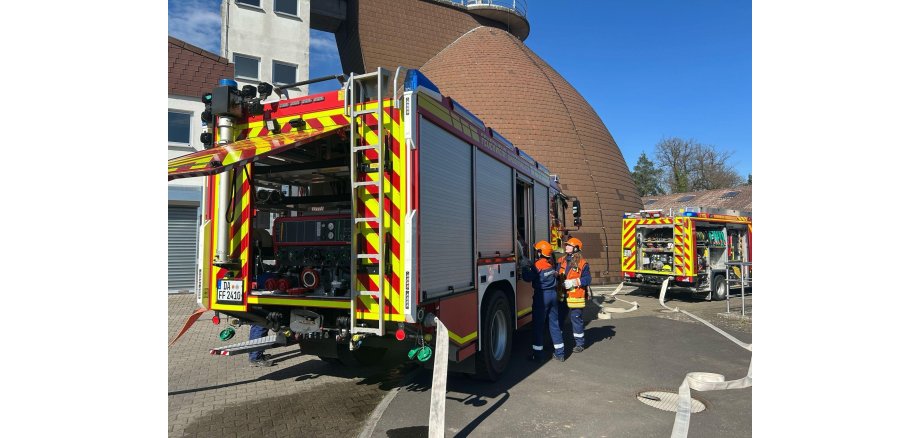 Auf dem Bild sieht man 2 Feuerwehrautos und wie an der Kläranlage geübt wurde