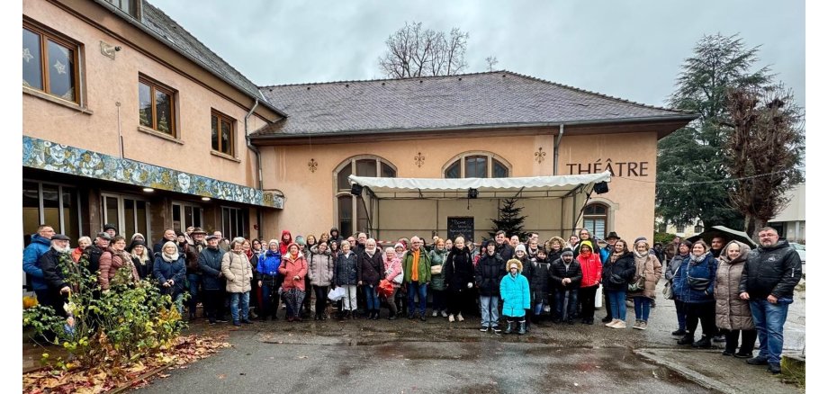 Man sieht eine große menschengruppe, die sich für ein Bild vor dem Theater aufgestellt hat