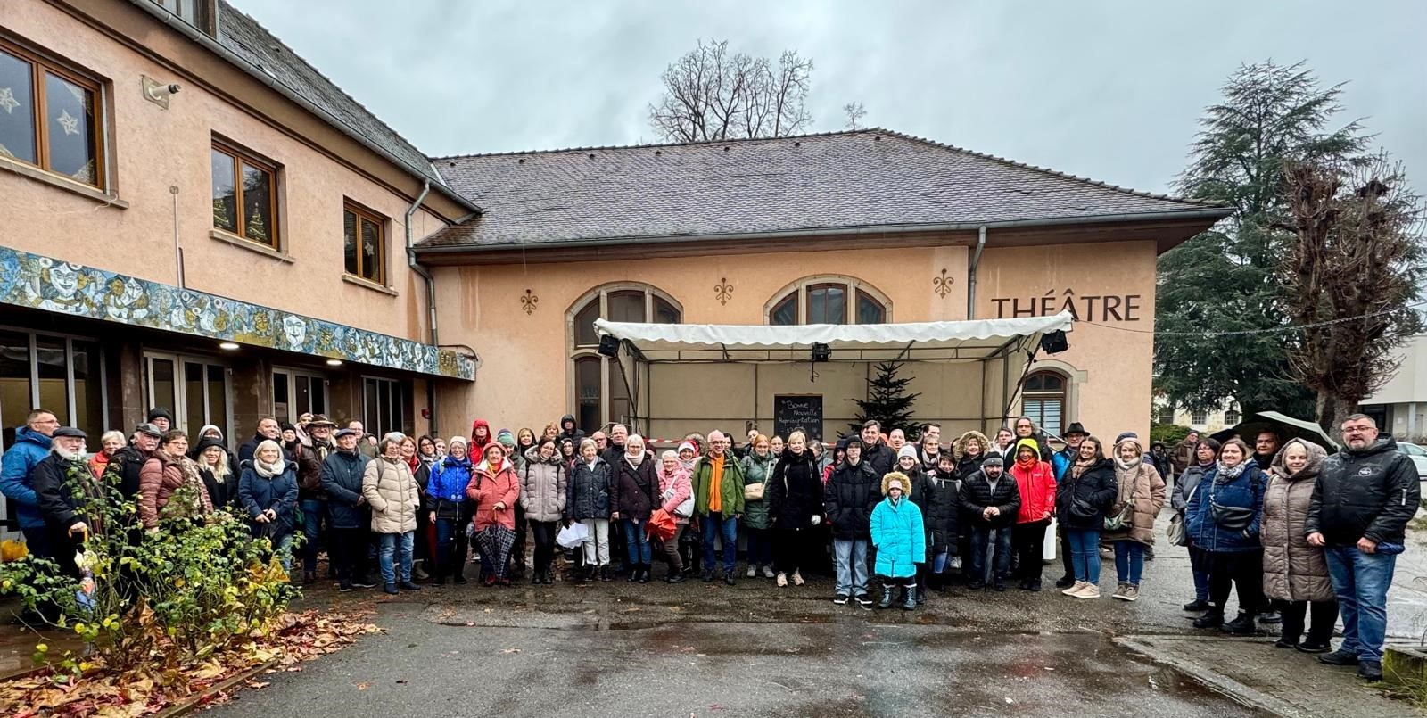 Man sieht eine große Menschengruppe, die sich für ein Bild vor dem Theater aufgestellt hat