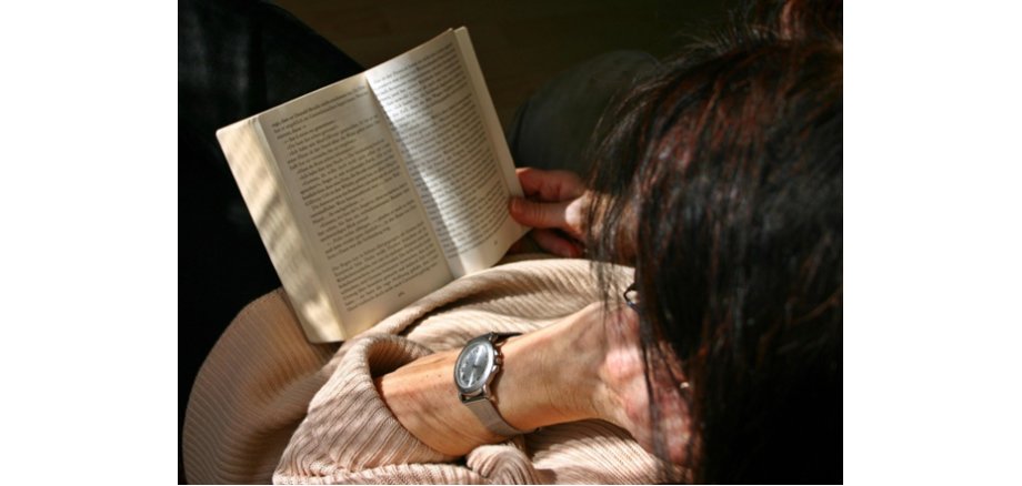 Person liest ein Buch, von oben fotografiert