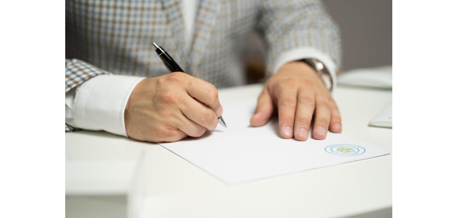 Person unterschreibt ein Dokument mit einem notariellen Stempel