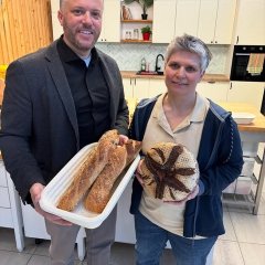 Auf dem Bild sieht man den Bürgermeister Dominik Stadler und eine Frau. Beide halten frisch gebackenes Brot/Baguette in der Hand. 
