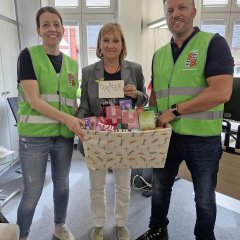 Auf dem Bild sieht man den Bürgermeister Dominik Stadler und Frau Spiehl sowie eine Frau die einen Geschenkkorb in der Hand hält.