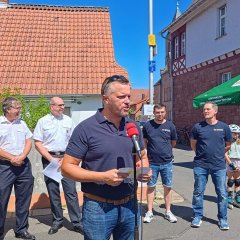 Man sieht den Bürgermeister Dominik Stadler und die Feuerwehr von Harpertshausen.