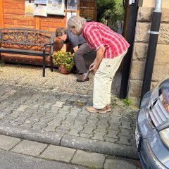 Auf dem Bild sieht man ein ältere Frau die sich nach Vorne bückt.