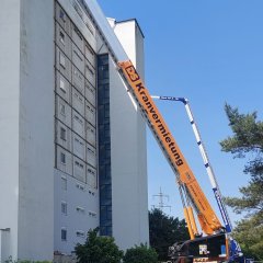 Auf dem Bild sieht man die kaputte Fassade des Hochhauses im Erloch sowie einen Kran.