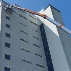 Auf dem Bild sieht man die kaputte Fassade des Hochhauses im Erloch sowie einen Kran.