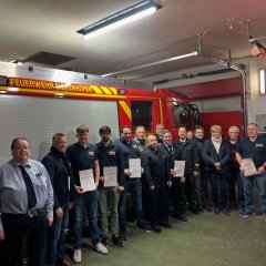 Man sieht die freiwillige Feuerwehr Sickenhofen. Im Hintergrund ist ein Feuerwehrauto.