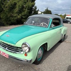 Auf dem Bild sieht man ein altes grünes Auto.