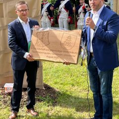 Auf dem Bild sieht man den Bürgermeister der Stadt Babenhausen und den Bürgermeister der Stadt Lichtentanne, die ein Holzbrett hochhalten.