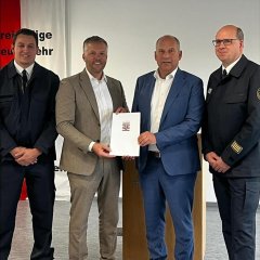 Man sieht wie der Bürgermeister Dominik Stadler eine Urkunde in der Hand hält. 