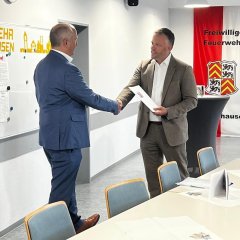 Man sieht wie der Bürgermeister Dominik Stadler und ein anderer Mann sich die Hand schütteln.
