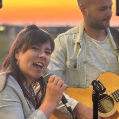 Man sieht eine Frau die singt und einen Mann der Gitarre spielt.