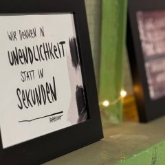 Man sieht einen Bilderrahmen und ein Bild mit einem Spruch