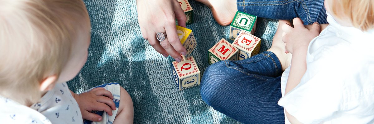 Titelbild zur Kindertagespflege, Spielende Kinder mit Erwachsenem Ausschnitt